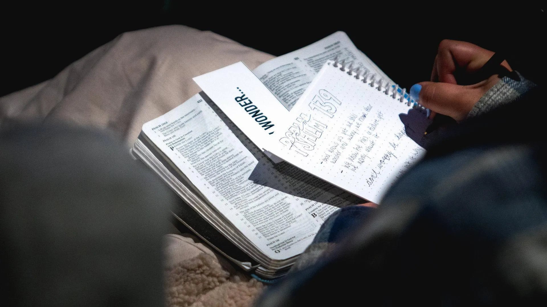 Handwritten notes in a notebook beside an open Bible